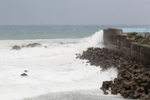 Штормовое море во время тайфуна, волны, разбивающиеся о барьерную стену — стоковое фото