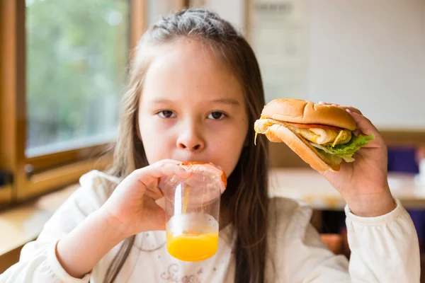 Flicka med hamburgare och apelsinjuice — Stockfoto