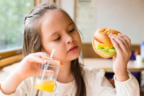 Flicka med hamburgare och apelsinjuice — Stockfoto