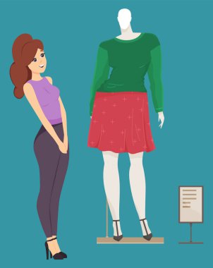 Vitrinde manken kıyafetlerini seçen tatlı bir kız. Alışveriş merkezinde vitrinin yanında duran kadın.