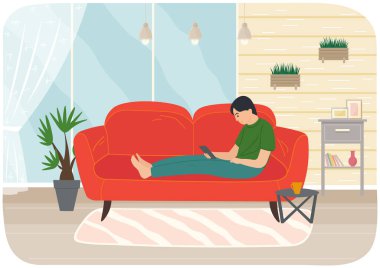 Genç adam tabletle kanepede oturuyor, uzaktan çalışıyor, sosyal medyayı izliyor, internete servis yapıyor.