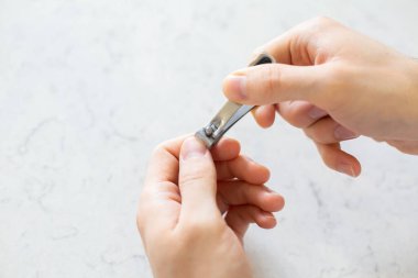 Tırnak makasıyla. Mermer zeminde tırnak kesmek.