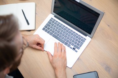 İnce dizüstü bilgisayarı ve cep telefonuyla ev ofisinin çalışma alanının en üst görüntüsü. Mobil bilgisayarda çalışıyor, boş ekran ve kopyalanmış boşluk