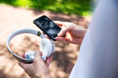 Bağlantı, cep telefonu ve kablosuz kulaklık. Erkek eli cep telefonu, akıllı telefon ve modern beyaz kablosuz kulaklık tutuyor..