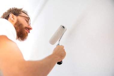 Boya silindirli duvar boyası. İş yerinde bir boyacı..