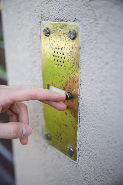 Gros plan d'une main masculine pressant un bouton sur une sonnette extérieure avec un interphone. — Photo