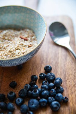 Sağlıklı kahvaltı. Yaban mersini ve granola, müsli, tahtadan bir tahtanın üzerinde yulaf ezmesi.. 