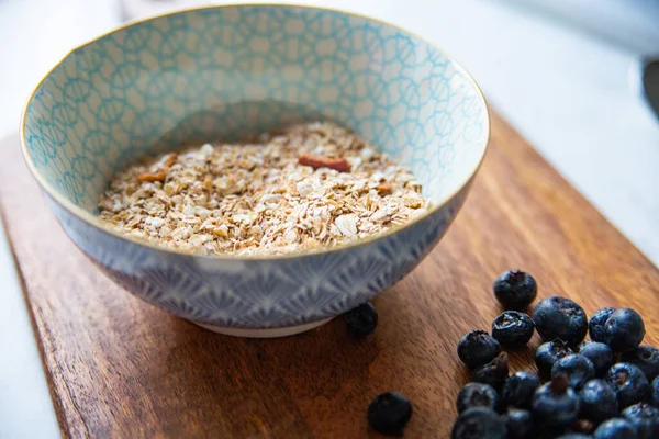 Granola, muesli, oatmeal in a bowl and blueberry on a wooden cutting board. — Stock Photo, Image