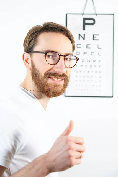 Young Bearded Man Smiling Looking Camera Reading Eye Test Chart — Zdjęcie stockowe