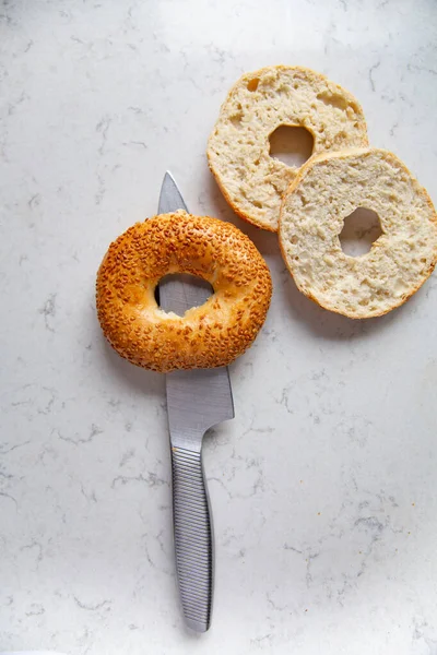 Two Bagels Sesame Seeds Whole Halved Knife Marble Kitchen Worktop — Stock Fotó