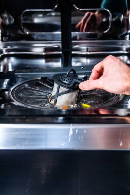 Erkek el bulaşık makinesinden filtre çıkarıyor.