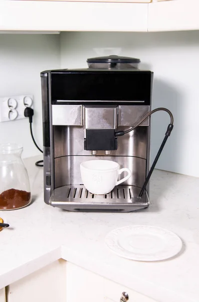 Making a coffee in a coffee machine at home, at office, in a bright kitchen. A coffee maker with an empty cup for a coffee on a drip tray cover.