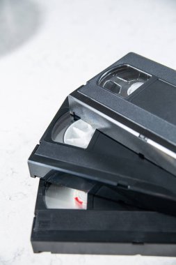 Three videotapes, video cassettes on a white, marble background. A pile of vintage VHS tapes without box, case, cover.