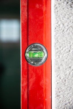 Rehber çizgilerinin arasında bir seviye baloncuğu olan kırmızı bir ruh seviyesi. Tadilat, inşaat alanı. Dikey bir konumda bir seviye ölçülüyor, test ediliyor. 