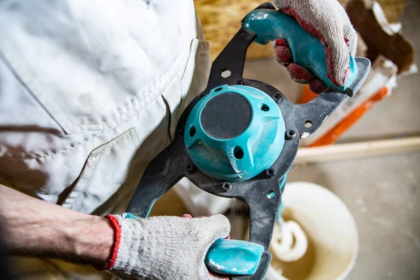 A construction worker holding a mixing paddle and mixing a plaster in a bucket. — Foto Stock