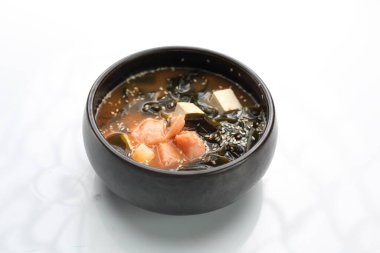 A bowl of misoshiru soup with salmon isolated on white.