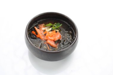 A fish broth with salmon, seasonal vegetables and Japanese spices, isolated on white.