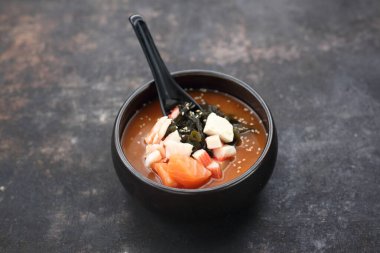 A close-up of a traditional Japanese soup. A misoshiru with salmon and seafood. 
