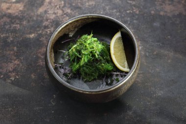 Bir salamura yosun Japon salatası. Bir goma wakame, üst görünüm, siyah taşlı bir arka plan üzerinde.