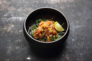 Siyah taşlı arka planda bir somon tartare..