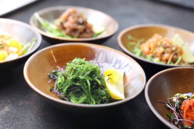 Siyah taşlı arka planda Japon yosun salatası, arka planda aperatiflerin bir kompozisyonu..