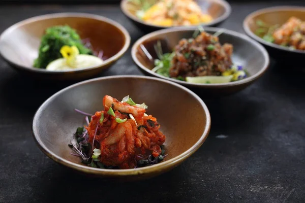 Un primer plano de una ensalada de kimchi coreano en un mostrador de piedra negro, composición de aperitivos en un fondo. — Foto de Stock