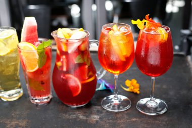 Renkli limonatalar, içkiler, çeşitli bardaklarda kokteyller, siyah taşlı arka planda..