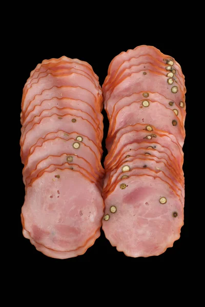 Krakowska, gedroogd, gerookte worst met groene peper, in plakjes, geïsoleerd op zwarte achtergrond. Snijd varkensvlees vleeswaren, bovenaanzicht, een packshot foto voor pakketontwerp. — Stockfoto