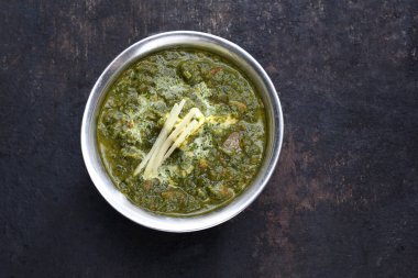 Ispanak körisinin üst görüntüsü, palak paneer, siyah taşlı arka planda bir doğu yemeği, yakın plan. Geleneksel Hint mutfağı.