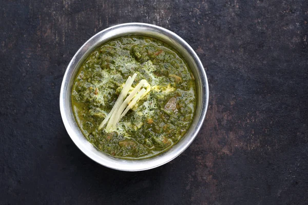 Top view of spinach curry, palak paneer, an oriental dish, on black stony background, close-up. Traditional Indian cuisine. — Stock Photo, Image