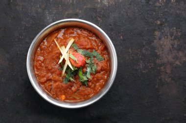 Vindaloo, köri, doğu yemeği, siyah taşlı arka planda. Geleneksel Hint mutfağı. Balkabağı püresi, domates, et ya da balığa dayanan sos, kişniş ile birlikte, kopyasal alan ile yakın plan..