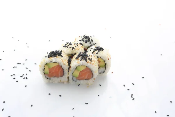 5 piece uromaki sushi set with salmon, avocado and philadelphia cheese, on a white background with scattered black sesame seeds. Japanese cuisine delicacy. — Stock Photo, Image