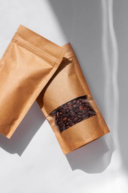 Kahverengi kese kağıtları kahve çekirdekli çantalar beyaz arka planda gölgelenmiş gölgeler. Gıda için ambalaj malzemeleri şablonu mockup.Kopçası ve çay yaprakları için pencere ile paketleme, dikey pankart.
