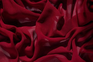 Pürüzsüz, burgundy şifon kumaş, soyut bir arka plan. Koyu kırmızı şarap ipek kumaş. Tasarım için açık yüzey üzerinde lüks kumaş. Lüks Sevgililer Günü arkaplanı. Dalgalı mat dokulu malzeme