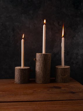 Sıfır atık konsepti, kahverengi masada doğal ahşap mum tutacakları. Karanlık arka planda mum yakmak. Spa sağlığı gevşemesi, çevre dostu ev tasarımı. Plastik iç dekorasyon yok.