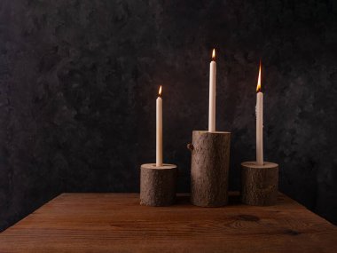 Sıfır atık konsepti, kahverengi masada doğal ahşap mum tutacakları. Karanlık arka planda mum yakmak. Spa sağlığı gevşemesi, çevre dostu ev tasarımı. Plastik iç dekorasyon yok.