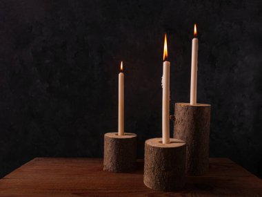 Sıfır atık konsepti, kahverengi masada doğal ahşap mum tutacakları. Karanlık arka planda mum yakmak. Spa sağlığı gevşemesi, çevre dostu ev tasarımı. Plastik iç dekorasyon yok.