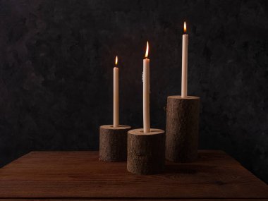 Sıfır atık konsepti, kahverengi masada doğal ahşap mum tutacakları. Karanlık arka planda mum yakmak. Spa sağlığı gevşemesi, çevre dostu ev tasarımı. Plastik iç dekorasyon yok.