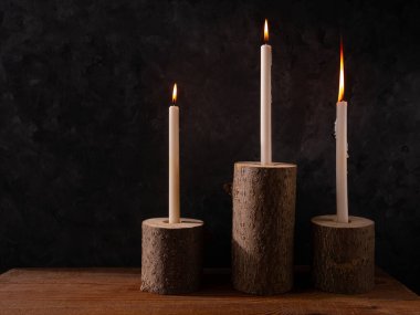 Sıfır atık konsepti, kahverengi masada doğal ahşap mum tutacakları. Karanlık arka planda mum yakmak. Spa sağlığı gevşemesi, çevre dostu ev tasarımı. Plastik iç dekorasyon yok.