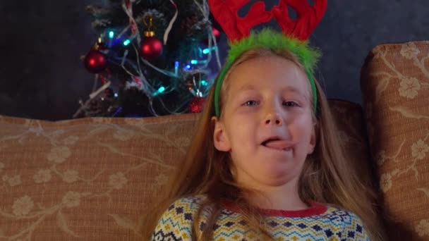 소녀가 웃으며 집에서 카메라로 얼굴을 바라본다 새해가 이빨없는 아이가 크리스마스 — 비디오