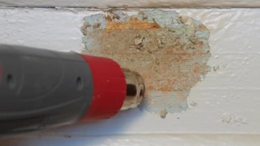 Ahşap kapı penceresinin ucuz restorasyonu. Restoratör marangoz boyalı tahta yüzeydeki boyayı yüksek ısı tabancası ve spatulayla soyar. Ev Yapımı Projesi. İç mimari.