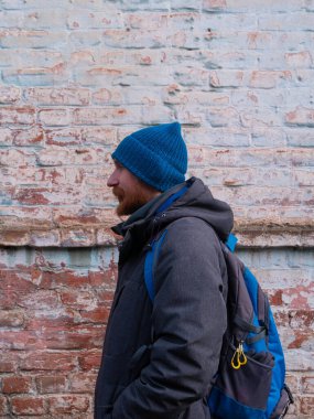 Genç kızıl sakallı adam cep telefonuyla konuşuyor mavi şapkalı gri ceketli adam tuğla duvarlı arka planda olumlu duygusal bin yıllık cevaplar akıllı telefon çağrısı. Yaşam tarzı iş mesafesi iletişimi.