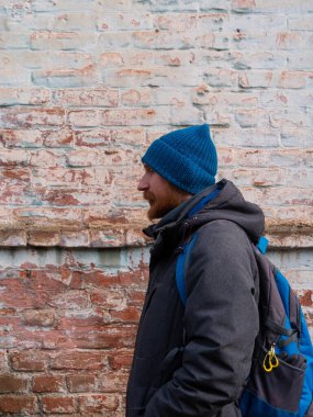 Genç kızıl sakallı adam cep telefonuyla konuşuyor mavi şapkalı gri ceketli adam tuğla duvarlı arka planda olumlu duygusal bin yıllık cevaplar akıllı telefon çağrısı. Yaşam tarzı iş mesafesi iletişimi.