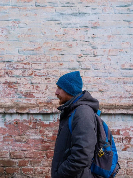 Genç kızıl sakallı adam cep telefonuyla konuşuyor mavi şapkalı gri ceketli adam tuğla duvarlı arka planda olumlu duygusal bin yıllık cevaplar akıllı telefon çağrısı. Yaşam tarzı iş mesafesi iletişimi.