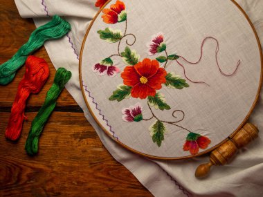 Çiçekler halka ahşap arka planda beyaz tekstil üzerine nakış işlerler. Geleneksel Ukrayna diş ipi nakış motifleri. El yapımı etnik kıyafetler masa örtüsü. Yeni normal tecrit Hooby el sanatları özel dersi