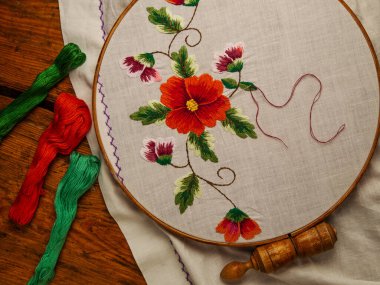 Çiçekler halka ahşap arka planda beyaz tekstil üzerine nakış işlerler. Geleneksel Ukrayna diş ipi nakış motifleri. El yapımı etnik kıyafetler masa örtüsü. Yeni normal tecrit Hooby el sanatları özel dersi