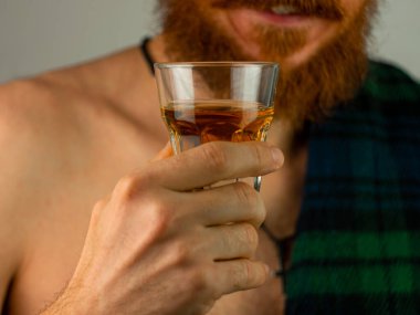 Geleneksel yeşil etekli İrlandalı sakallı adam elinde viski bardağıyla Aziz Patrick Günü 'nü kutluyor. Bıyıklı İskoç adam bar portresinde viski içiyor. 17 Mart İrlanda geçit töreni