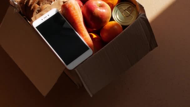 健康食品交付严酷的阴影 取消天然有机产品包装 捐赠箱新的普通智能手机网上购物安全商店送货 水果蔬菜胡萝卜苹果粒面包坚果 — 图库视频影像