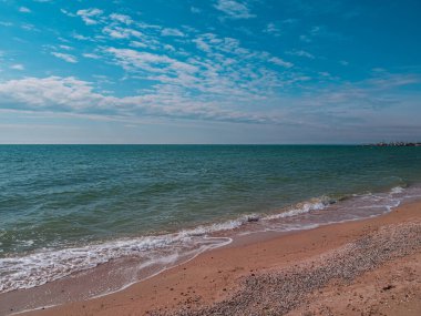Güneşli bir günde mavi deniz ve gökyüzü arkaplanı olan boş bir sahil. Güney manzaralı duvar kâğıdı, sonbahar yaz tatili sezonu. Bulanık kopya alanı olan canlı mavi su. Tatil köyü reklamı