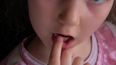 Sevimli anaokulu çocuğu süt dişini sallıyor ve gülümsüyor. Kalıcı 4K görüntülerle dişlerin değiştirilmesi. Koyu arkaplan. Korkmuş küçük kız 6-7 yaşlarında, kesici dişlerini kaybetmiş..